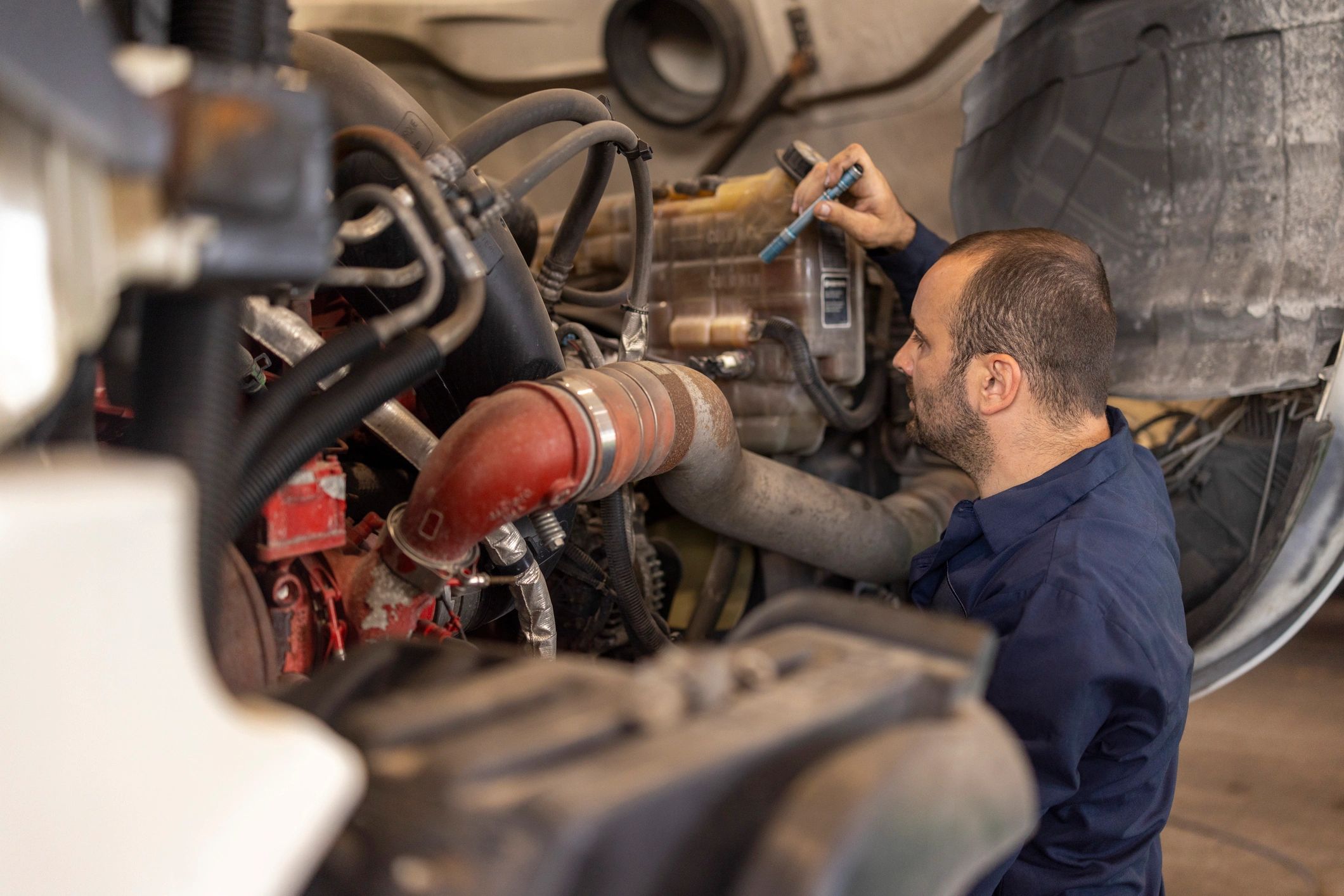 Mechanic inspecting a truck engine in a workshop